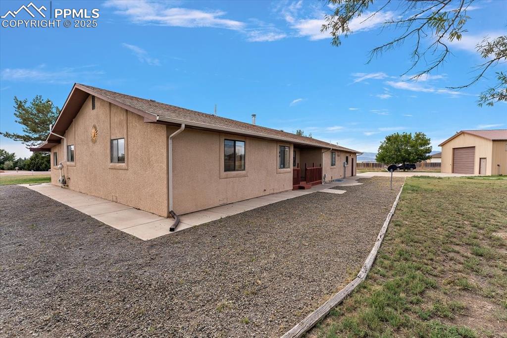 View of side of home featuring stucco siding and an outbuilding