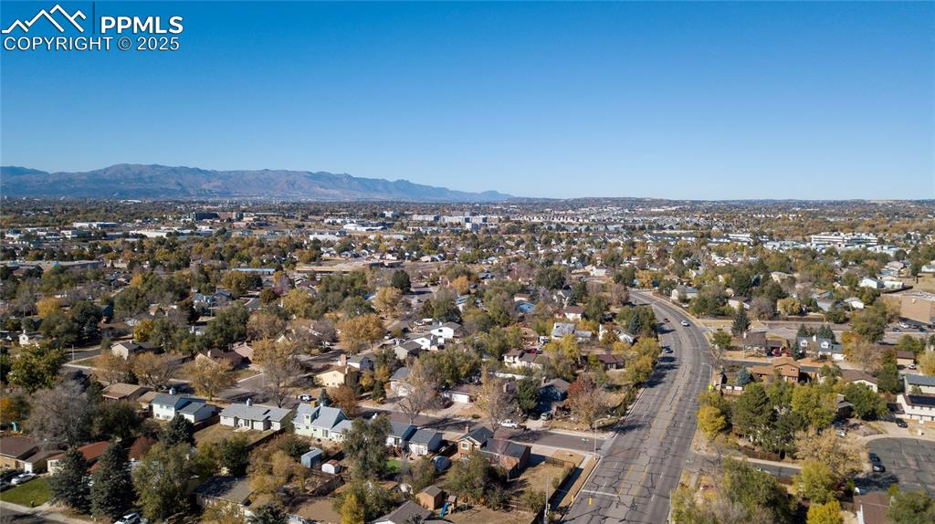 Aerial view of property and surrounding area with nearby suburban area and a mountain backdrop