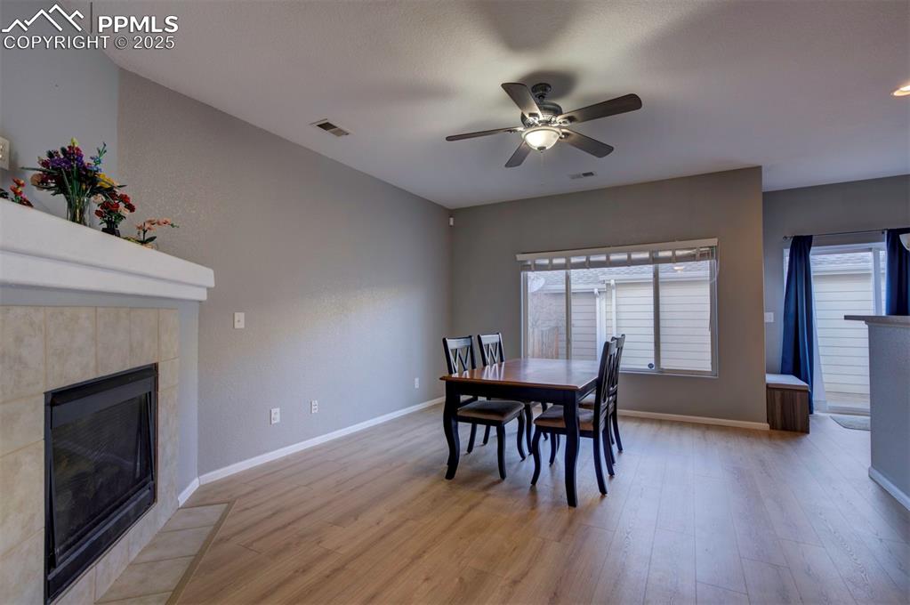 Dining area featuring a fireplace, light wood finished floors, and ceiling fan