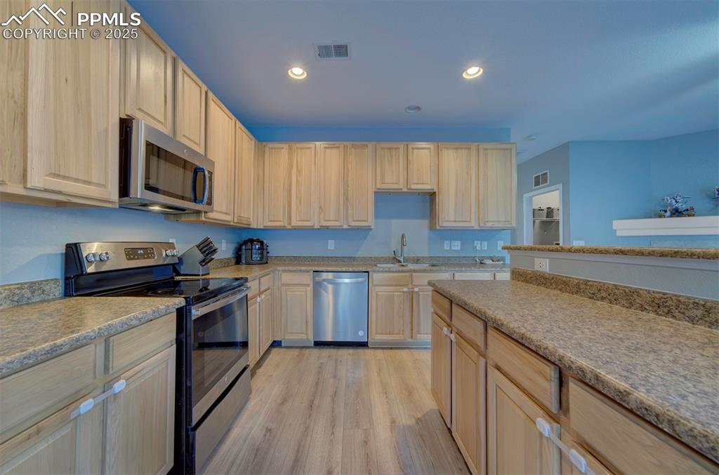 Kitchen with appliances with stainless steel finishes, recessed lighting, light brown cabinetry, and light wood finished floors