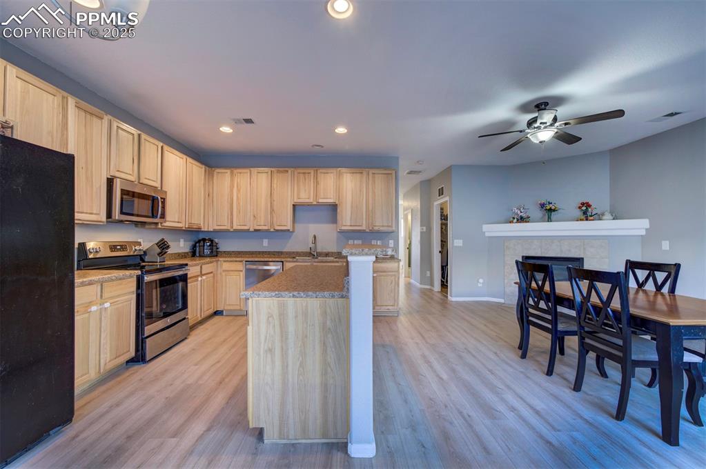 Kitchen with appliances with stainless steel finishes, light wood-style flooring, recessed lighting, light brown cabinets, and a center island
