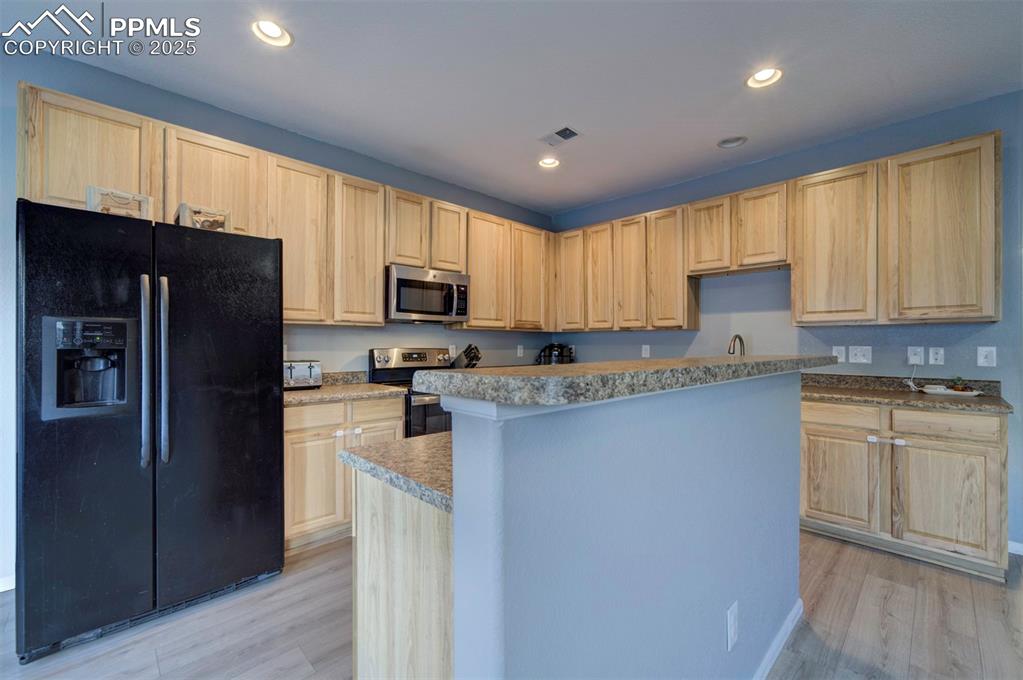 Kitchen featuring stainless steel appliances, light brown cabinetry, recessed lighting, light wood-style flooring, and light countertops