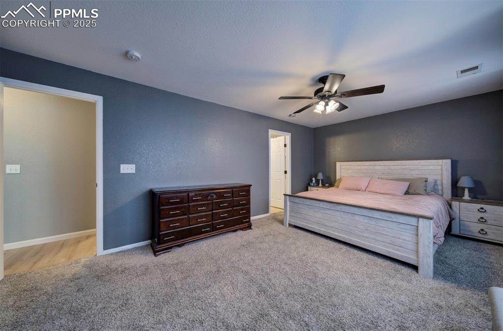 Bedroom featuring a textured wall, a ceiling fan, light carpet, and a textured ceiling