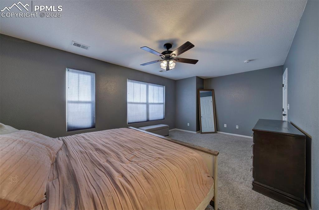 Bedroom featuring carpet floors, ceiling fan, and a textured ceiling