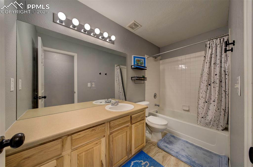 Full bath featuring shower / bath combo with shower curtain, vanity, and light tile patterned floors