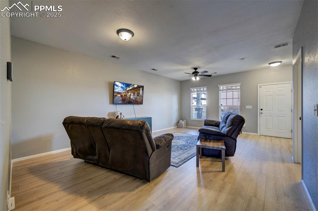 Living room featuring light wood-style floors, ceiling fan, and a textured ceiling