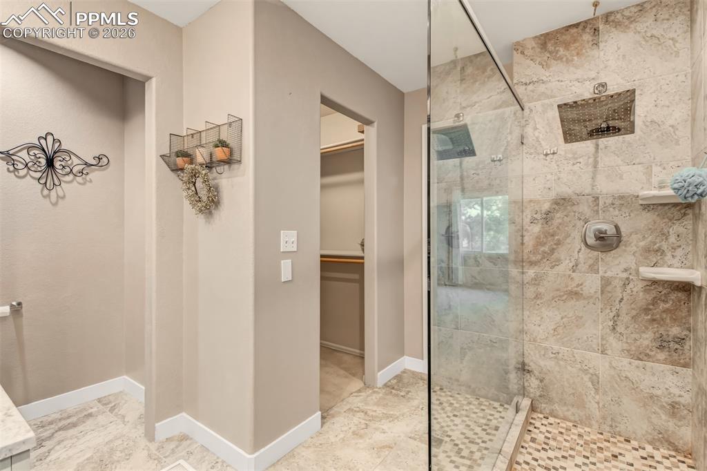 Master shower featuring a single glass side, open entry, tile surround and a rain shower head.