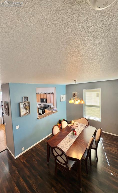 Dining room with dark wood-style floors, a textured ceiling, and hanging lights