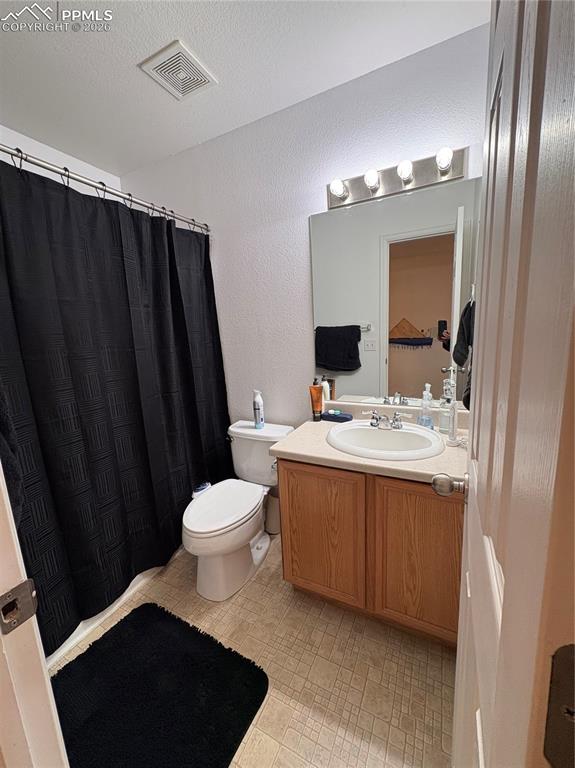 Bathroom featuring vanity, curtained shower, and a textured wall