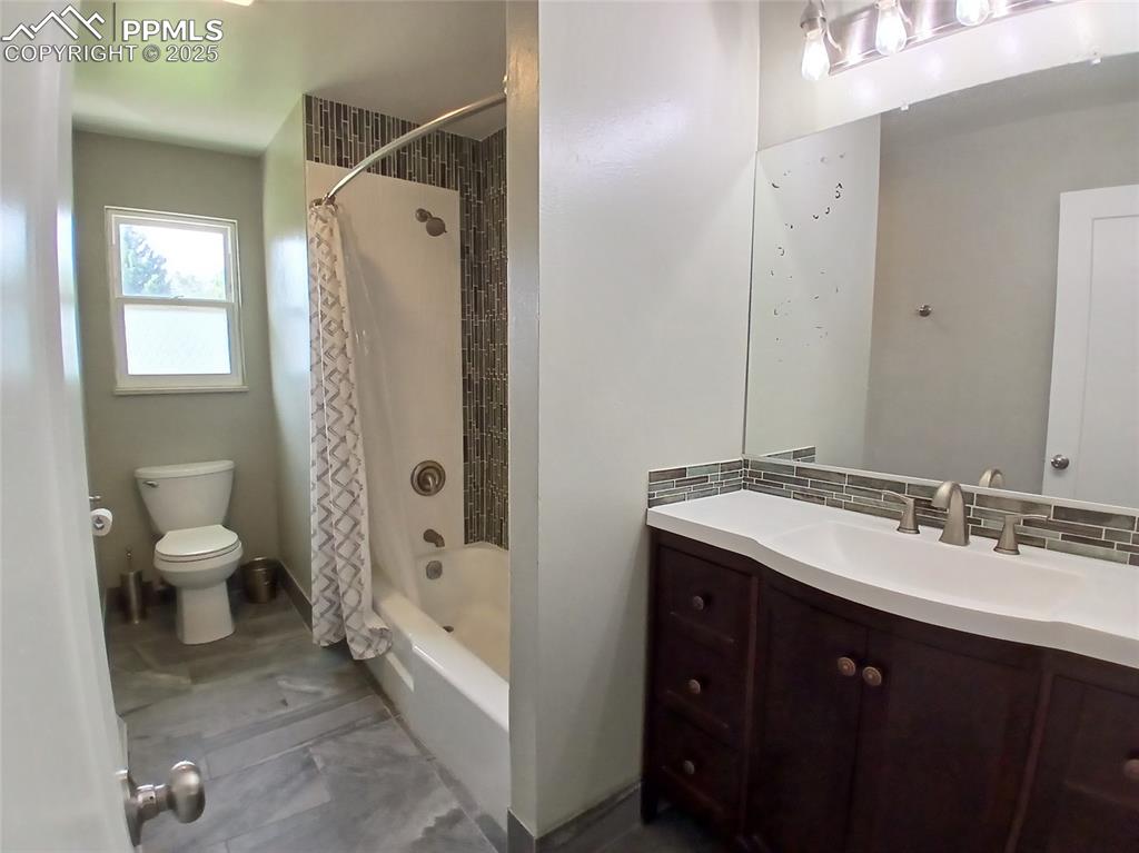 Full bathroom featuring tile floors, backsplash, shower / bath combination with curtain, vanity, and toilet