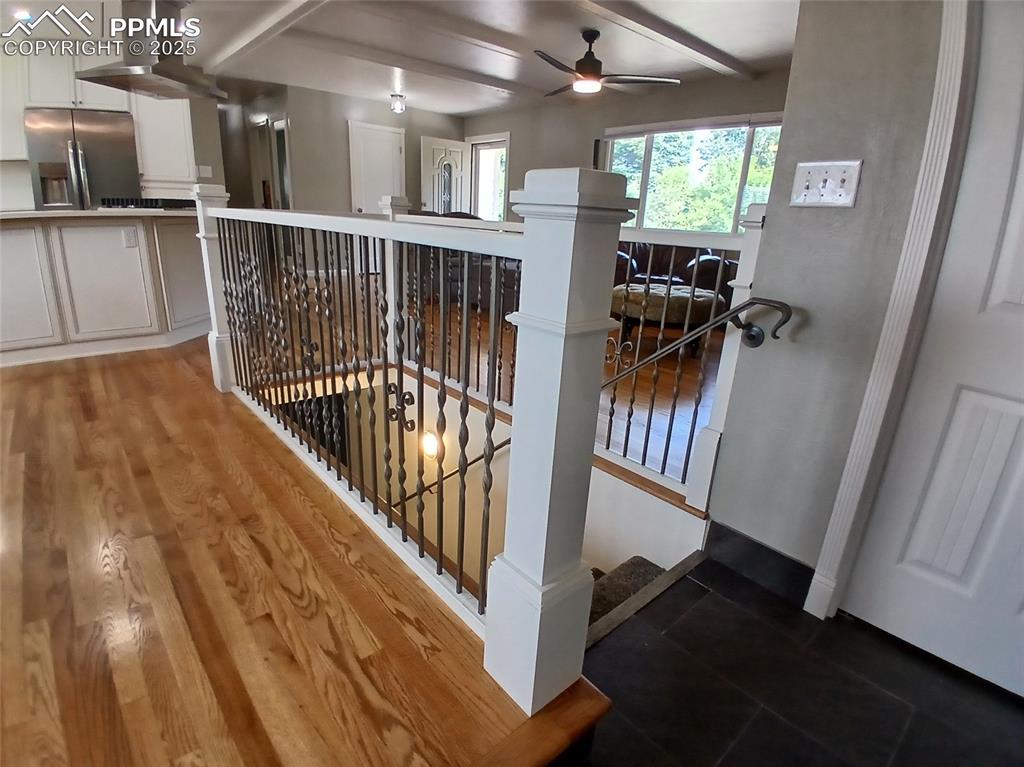 Stairway featuring wood-type flooring, beam ceiling, and ceiling fan