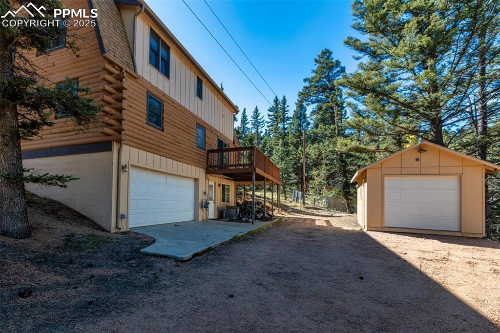 View of garage, entry to lower-level family room, 288 sq. ft. storage shed with lights, electricity and overhead door, fenced dog run at back.