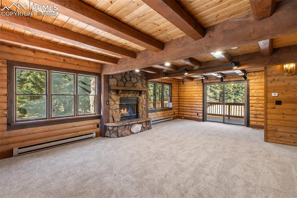 Unfurnished living room featuring a baseboard heating unit, carpet, a fireplace, rustic walls, and a wooden ceiling with exposed beams
