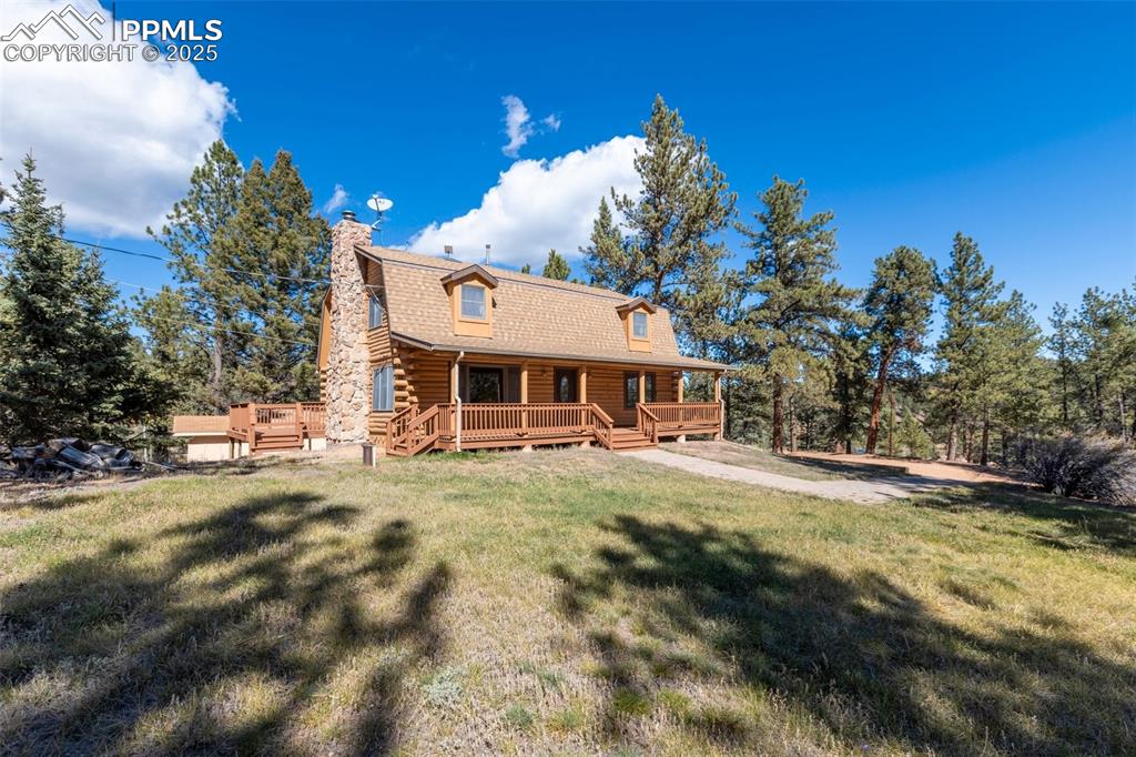 Log home with covered front porch, separate side deck off living room sliding doors and stone fireplace.