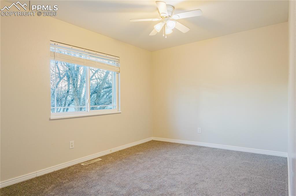 Carpeted spare room with baseboards and a ceiling fan