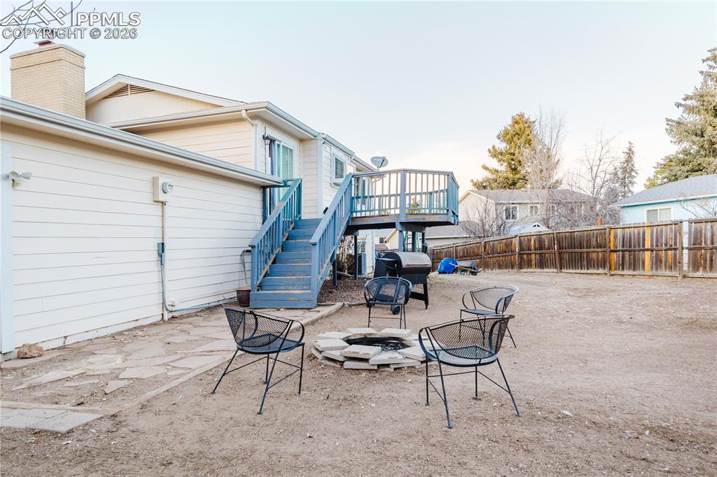 Fenced backyard with a patio area, an outdoor fire pit, a wooden deck, and area for grilling