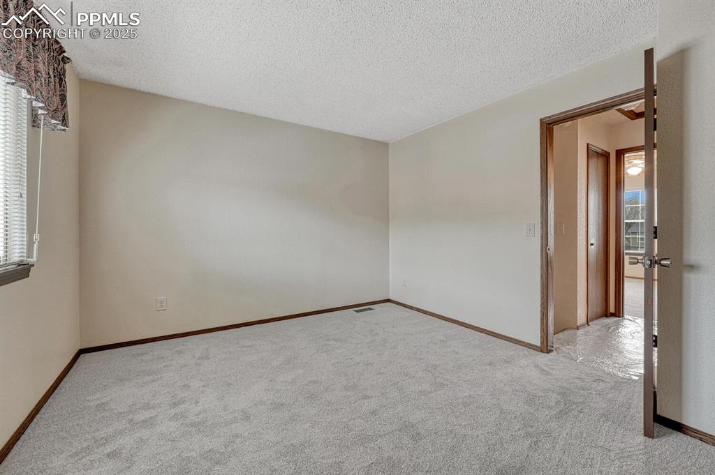 Carpeted empty room featuring a textured ceiling and baseboards