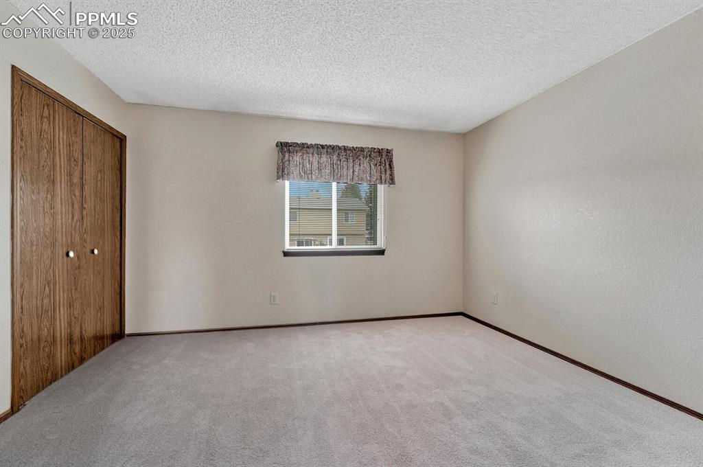 Unfurnished bedroom with a closet, a textured ceiling, and carpet