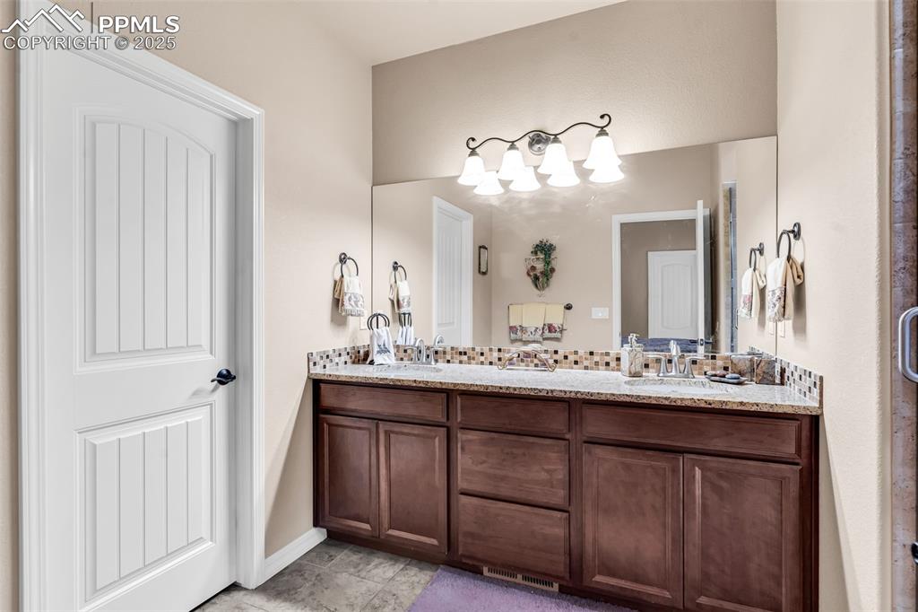 The luxe private bath offers a large vanity, two sinks, and custom walk-in shower with granite counters and custom tile accents throughout.