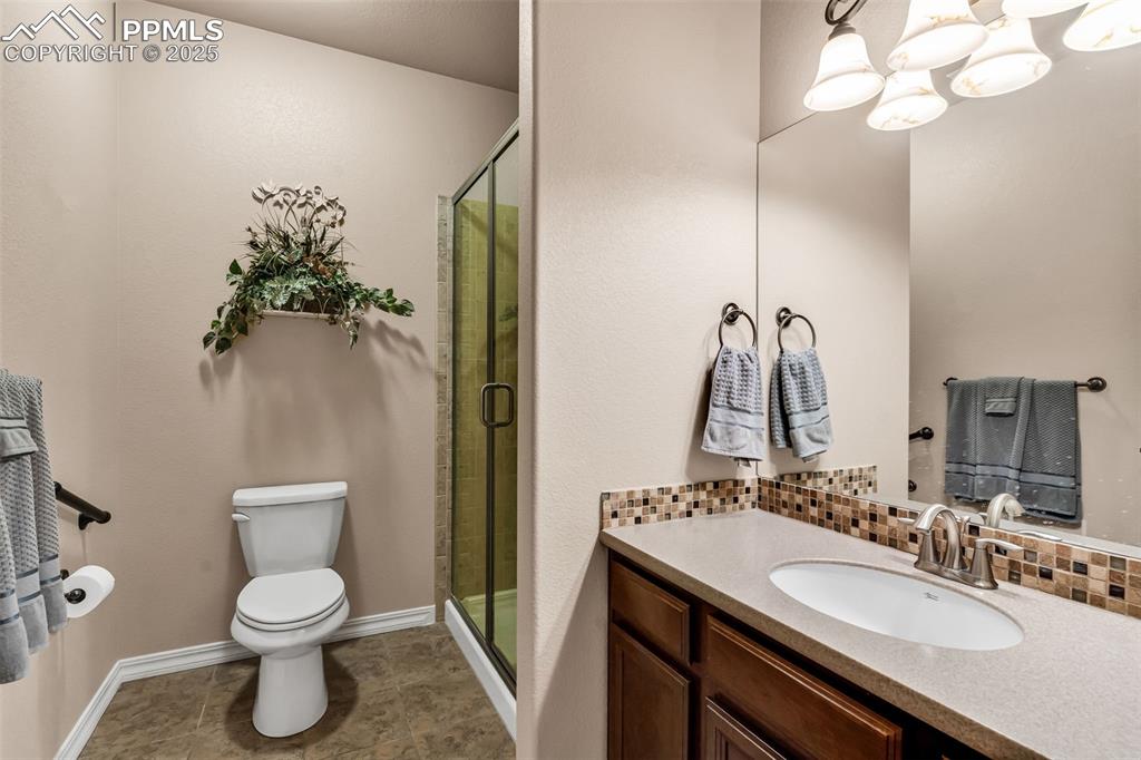 The spacious shared second bath has a custom walk-in shower and is finished with a granite counter, tile floors and custom tile accents.