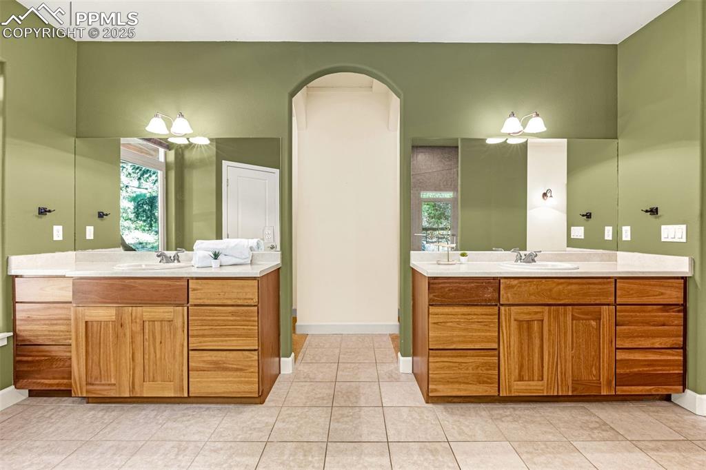 Full bathroom featuring two vanities, baseboards, and tile patterned floors