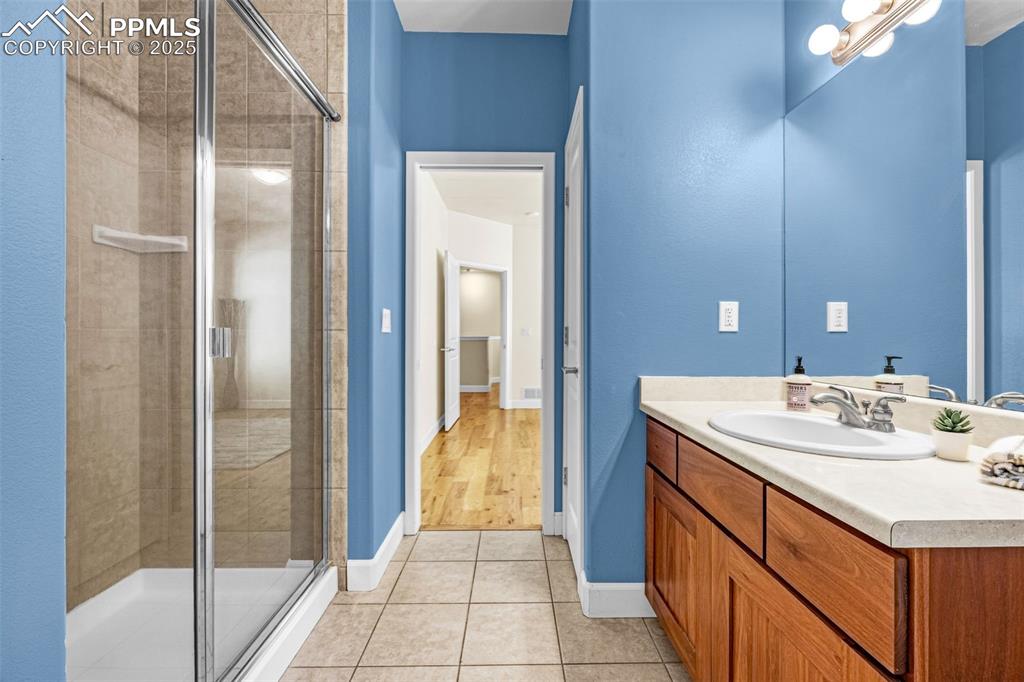 Bathroom with vanity, a stall shower, tile patterned floors, and baseboards