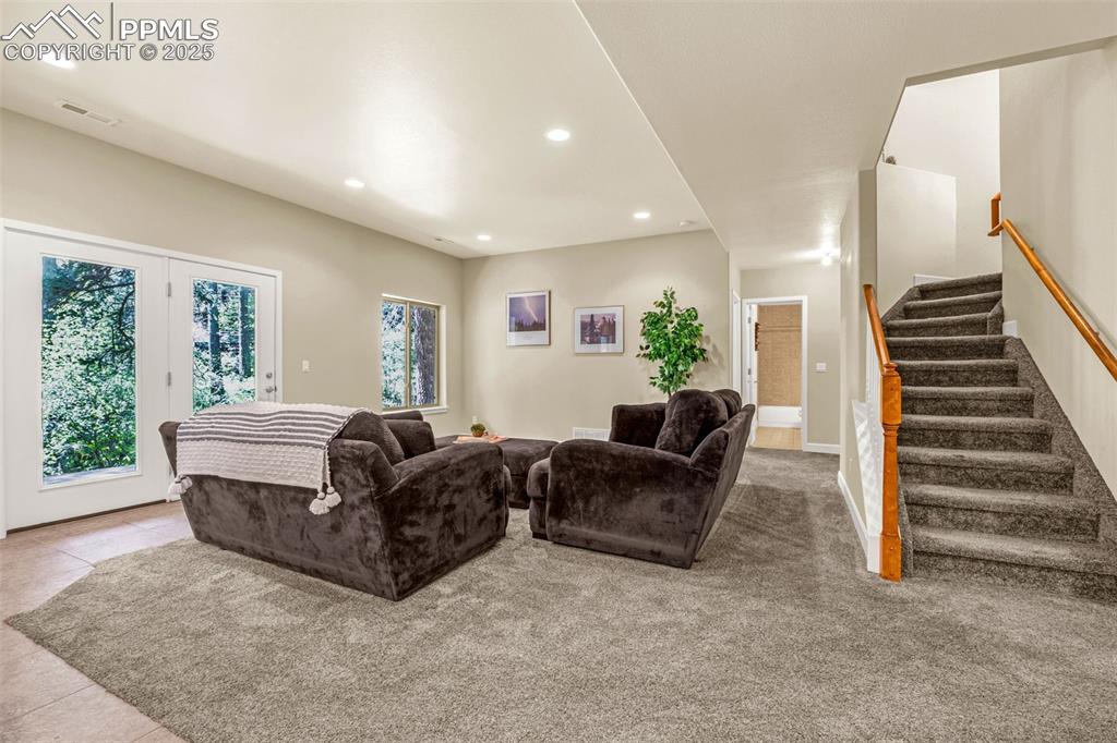 Tiled living room with recessed lighting and stairway