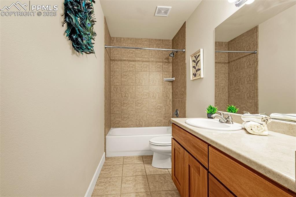 Full bath featuring vanity, toilet, tile patterned floors, shower / washtub combination, and baseboards