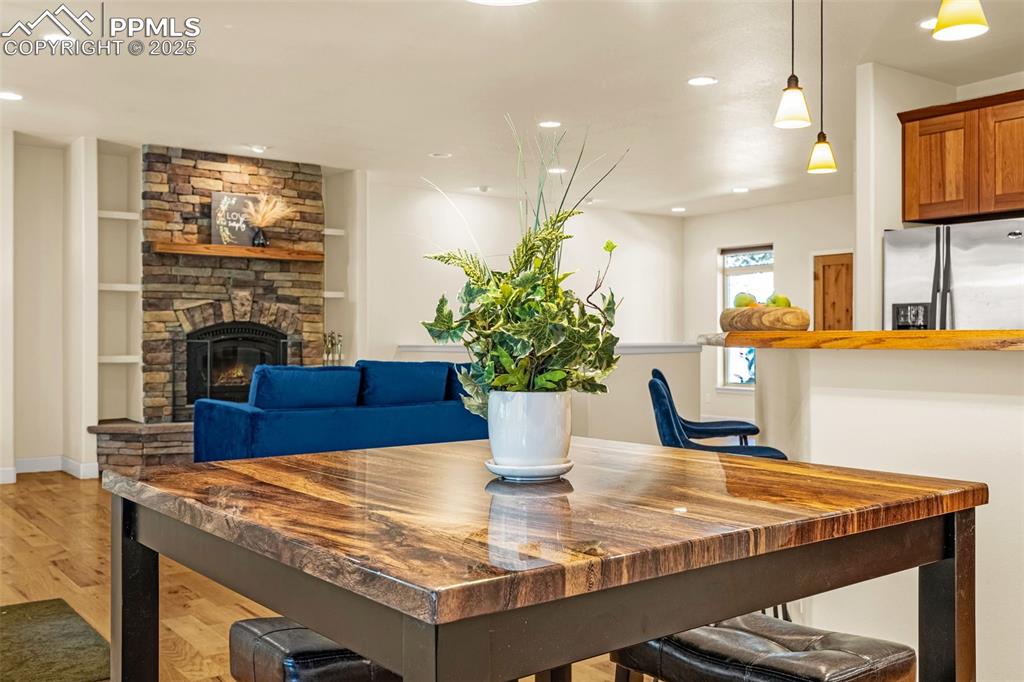 Dining area with light wood-style flooring, recessed lighting, a stone fireplace, built in features, and baseboards