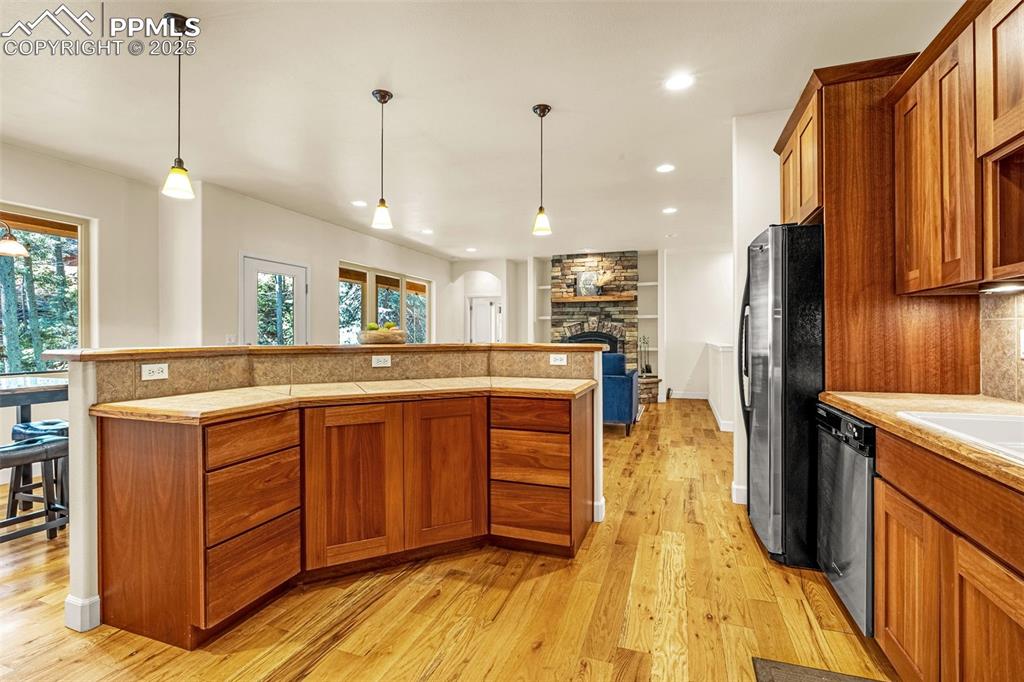 Kitchen featuring appliances with stainless steel finishes, brown cabinetry, light wood-style floors, light countertops, and recessed lighting