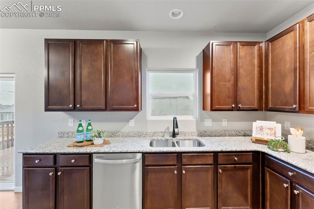 Kitchen featuring stainless steel dishwasher, light stone counters, and recessed lighting