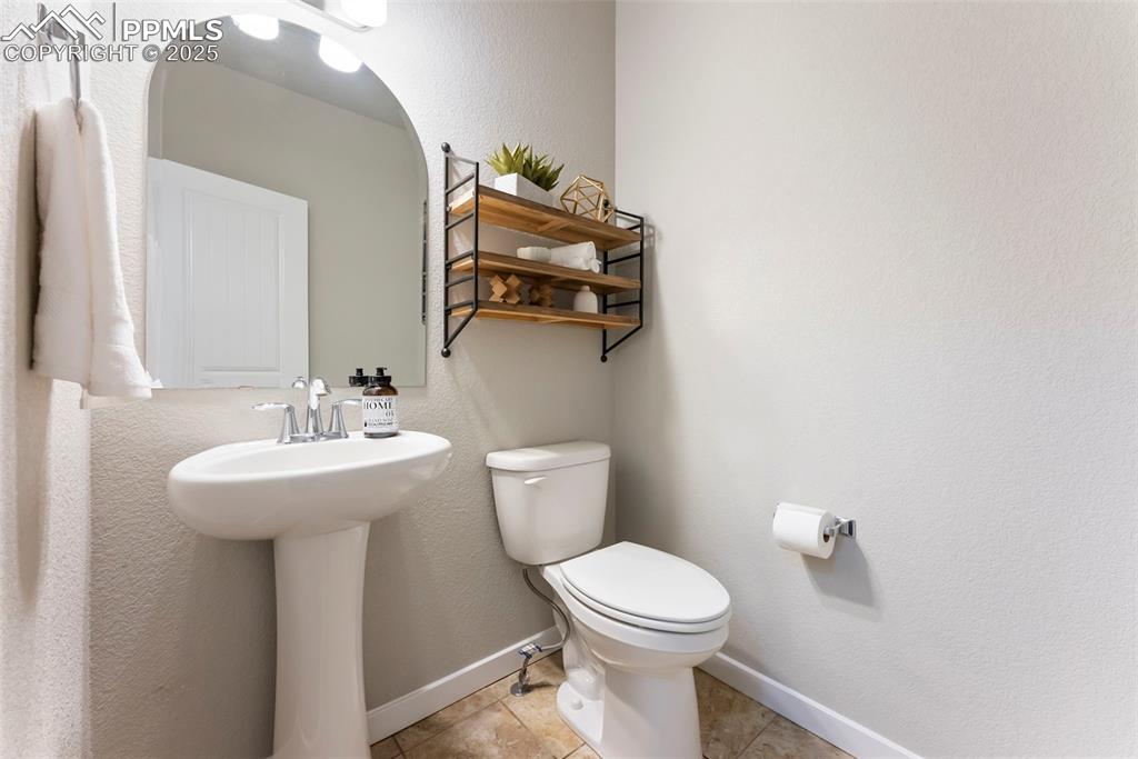 Half bathroom featuring a textured wall and light tile patterned flooring