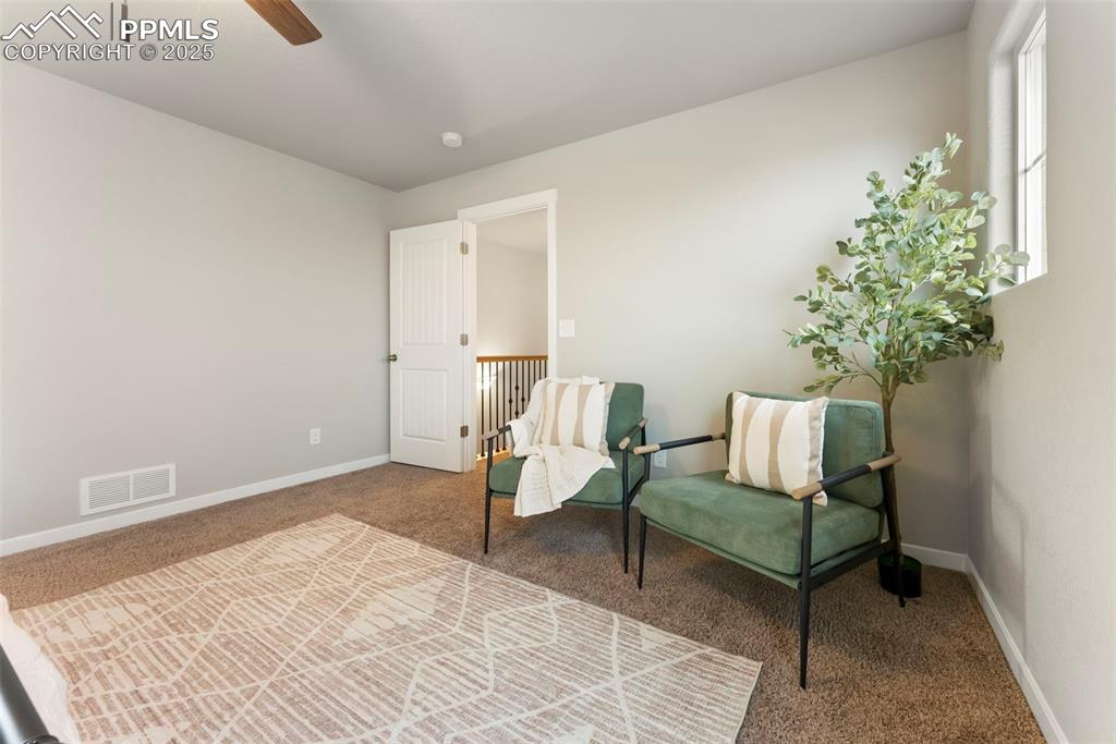 Living area with carpet floors and ceiling fan