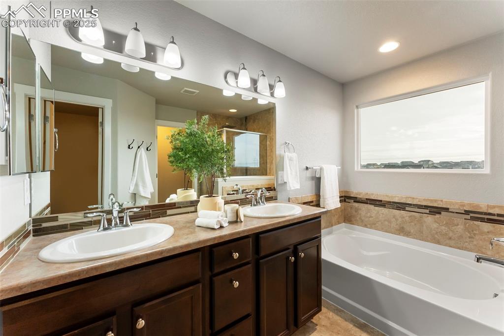 Full bathroom featuring a stall shower, a garden tub, double vanity, and recessed lighting
