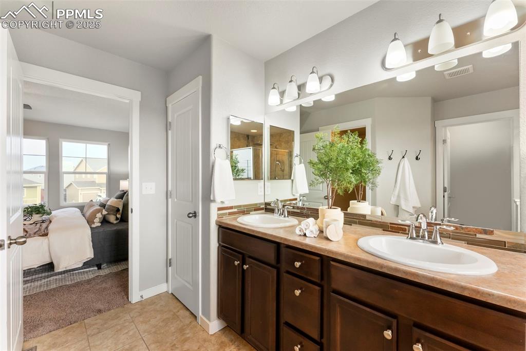 Ensuite bathroom featuring a stall shower, double vanity, and light tile patterned floors