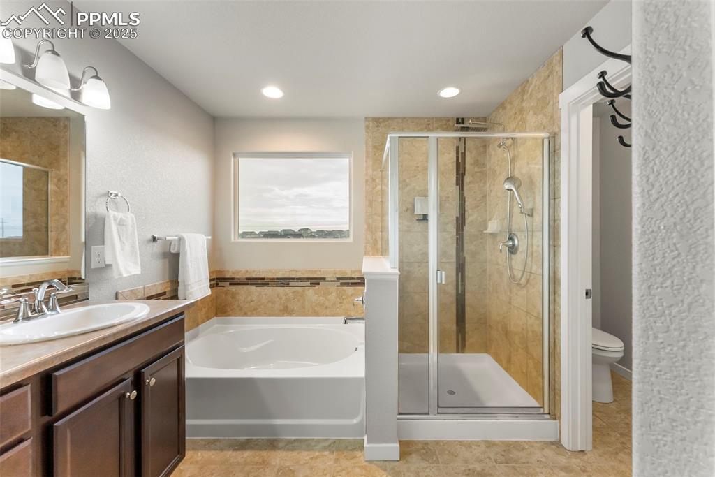 Bathroom featuring a garden tub, a stall shower, vanity, healthy amount of natural light, and a textured wall