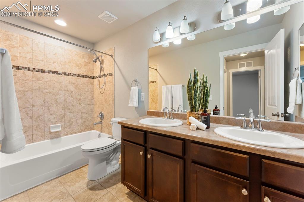 Bathroom with shower / bath combo with shower curtain, double vanity, light tile patterned floors, and recessed lighting