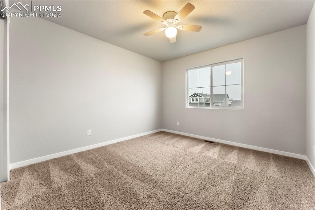 Empty room featuring carpet floors and a ceiling fan