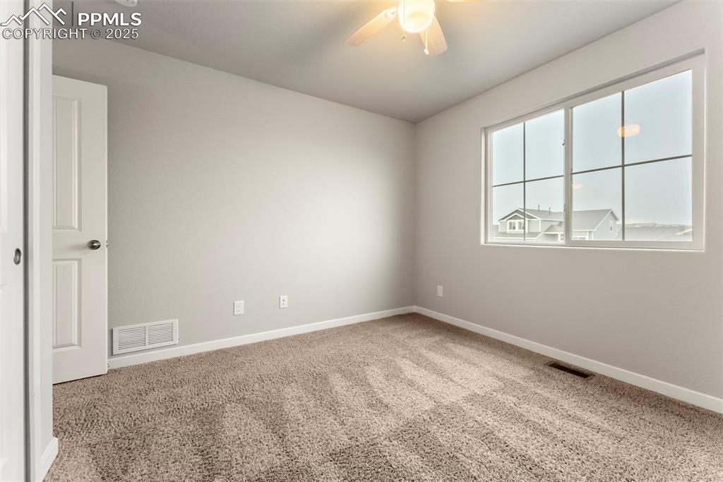 Carpeted spare room with baseboards and a ceiling fan