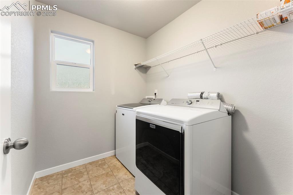 Washroom with independent washer and dryer and light tile patterned flooring