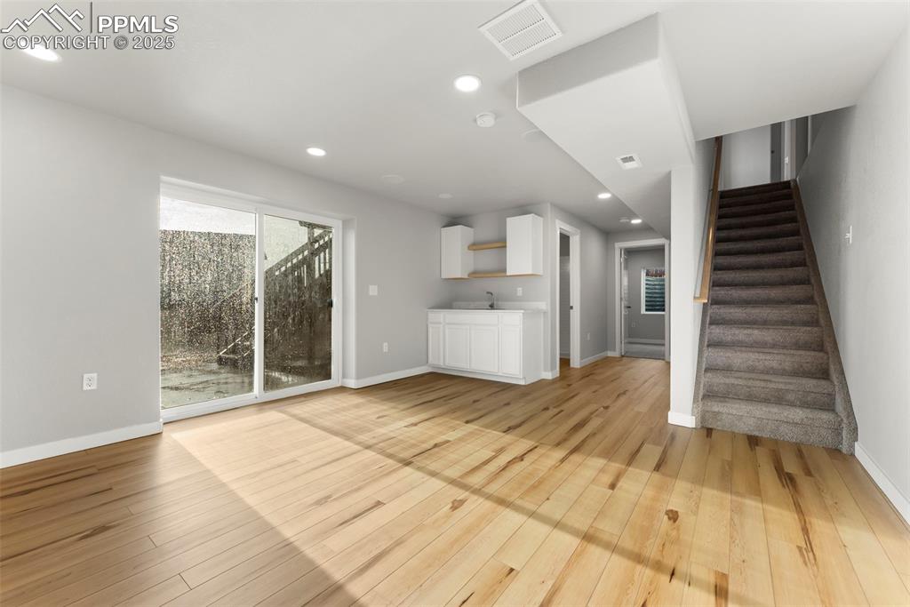 Unfurnished living room with recessed lighting, light wood-type flooring, and stairway