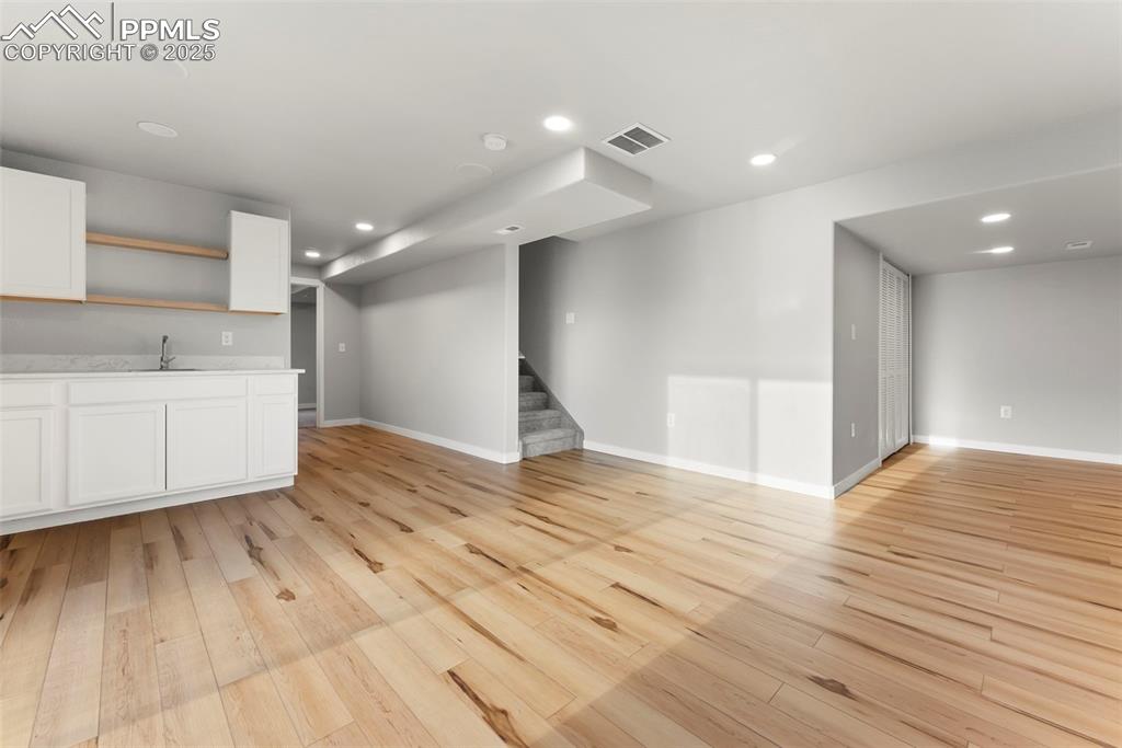 Unfurnished living room featuring stairway, recessed lighting, and light wood-style floors