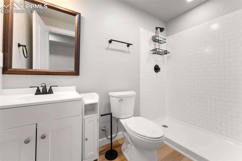 Bathroom with vanity, tiled shower, and light wood-style floors