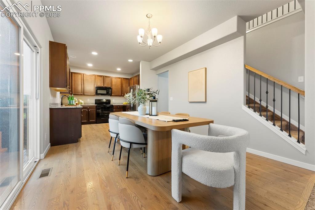 Dining room featuring light wood finished floors, a chandelier, stairs, and recessed lighting