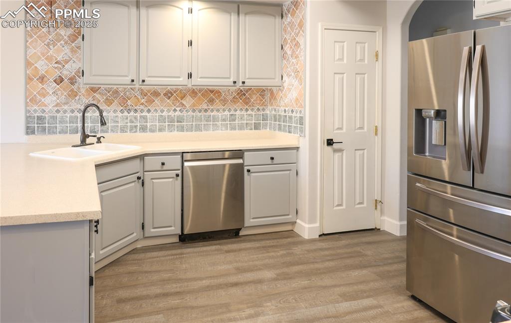 Kitchen featuring appliances with stainless steel finishes, backsplash, gray cabinets, and light wood finished floors