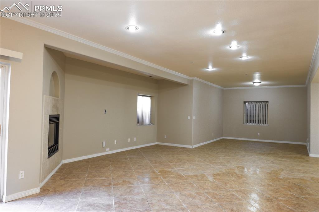 Spare room with a fireplace, ornamental molding, and light tile patterned flooring