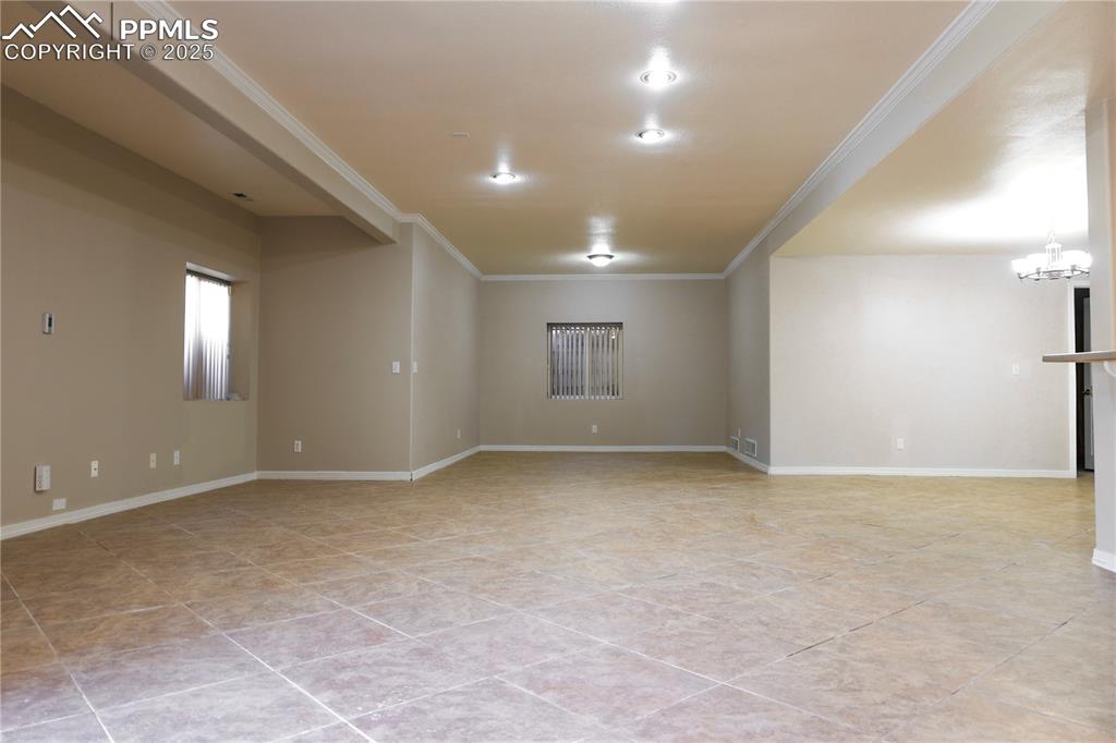 Unfurnished room featuring ornamental molding, a chandelier, and light tile patterned floors