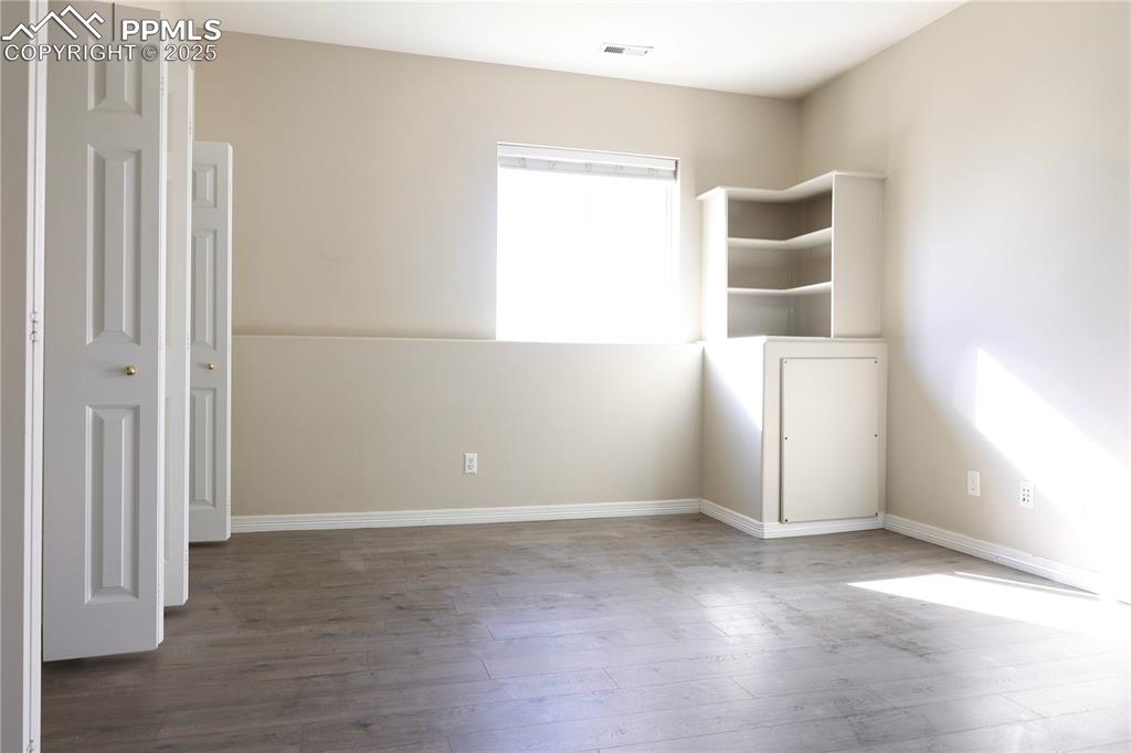 Unfurnished bedroom with wood finished floors and baseboards