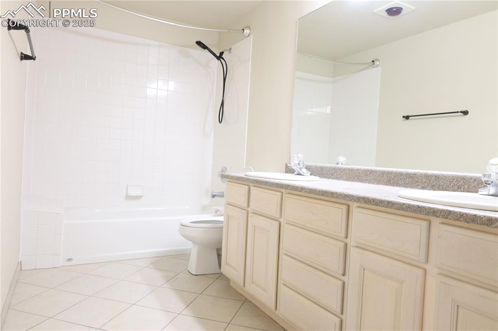 Bathroom with double vanity, light tile patterned floors, and shower / washtub combination