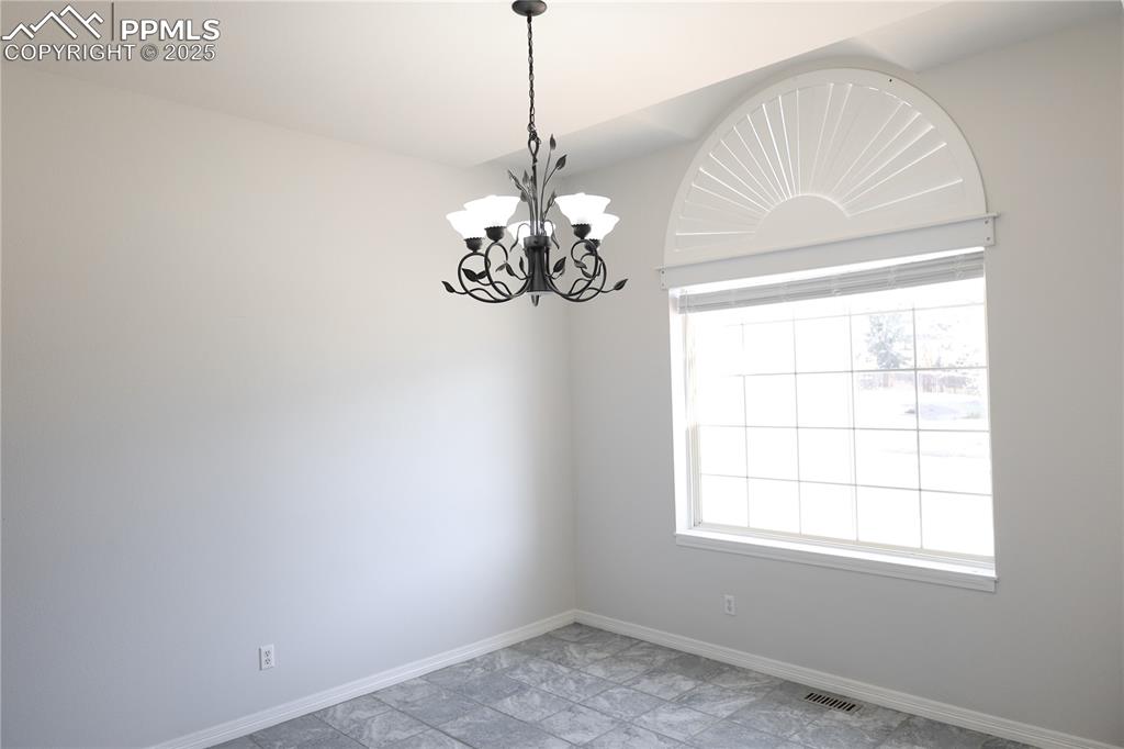 Spare room with a chandelier and baseboards